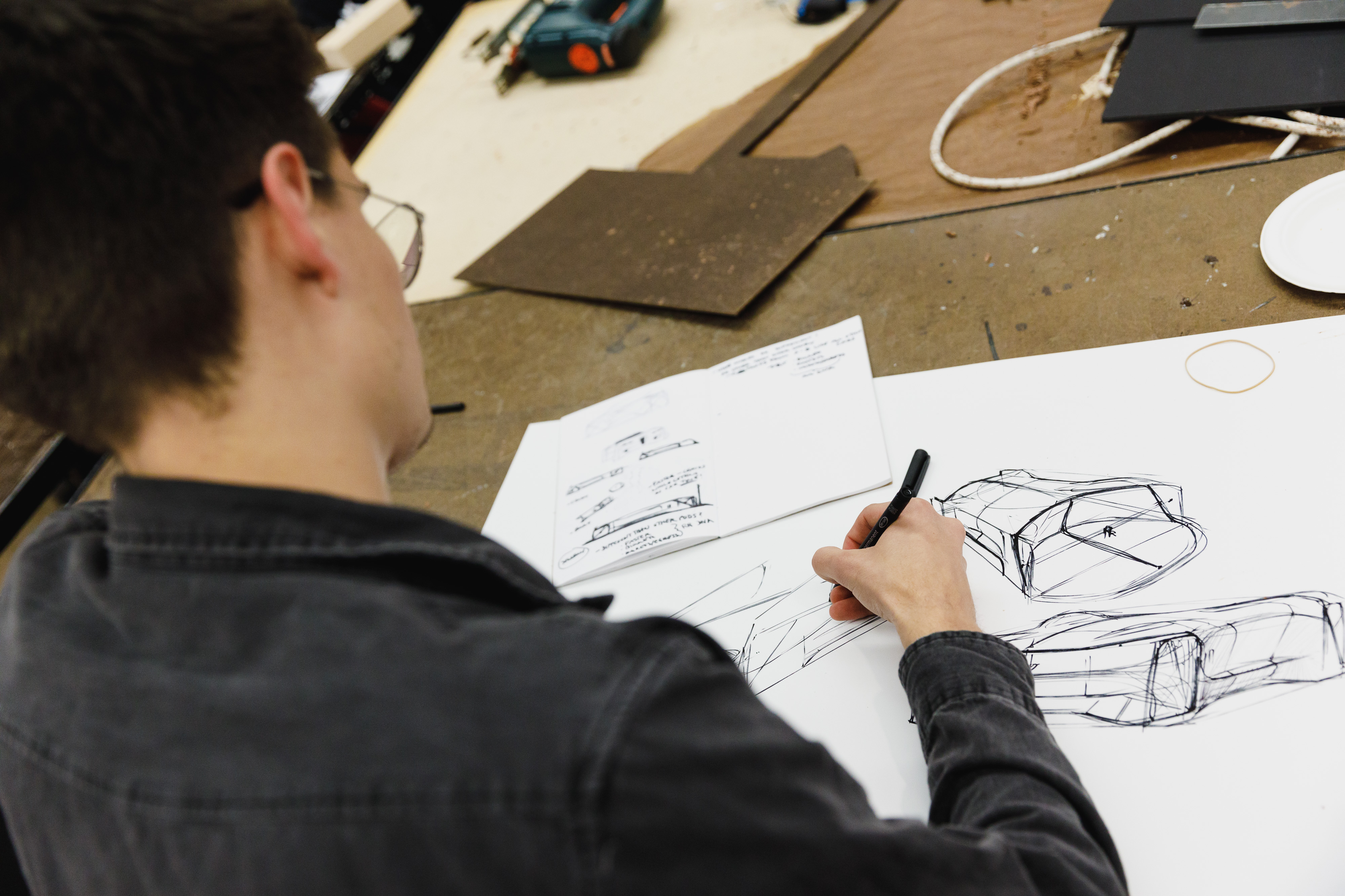 Over the shoulder shot of an ArtCenter student drawing a car in class. 