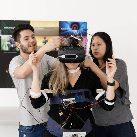 /man and woman assist a woman putting on a VR headset