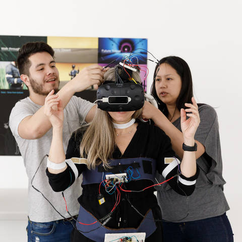 /Students adjusting VR Goggles on fellow student