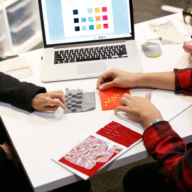 Two ArtCenter students review swatches in front of a computer