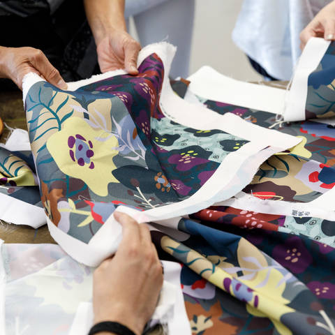 many hands holding pieces of patterned fabric