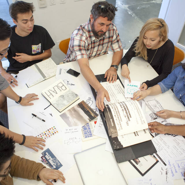 Four Creative Direction students discuss a project with their instructor