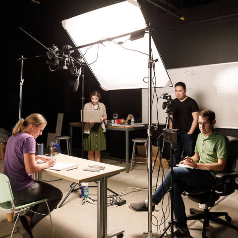 four people filming a drawing demo in a studio
