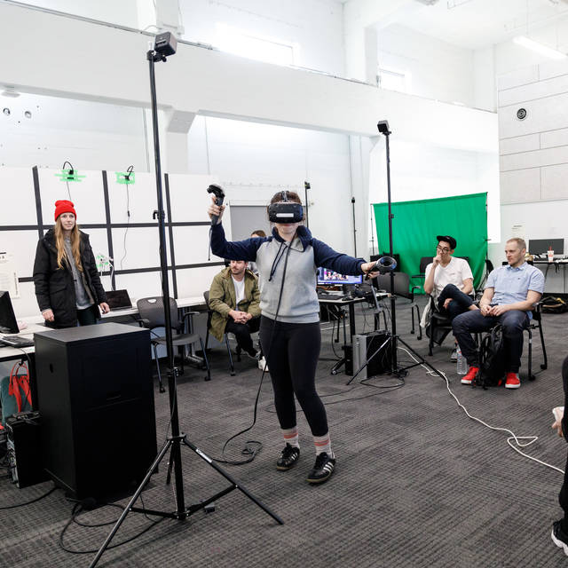 Woman wears vr headset while classmates look on