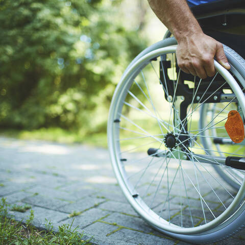 detail photo of a wheel chair wheel on a sidewalk
