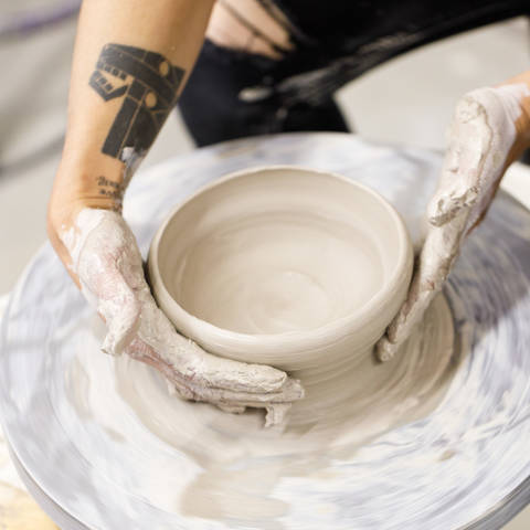 hands forming a pot on a pottery wheel