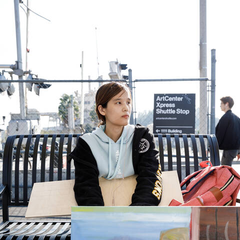 student waiting at a ArtCenter shuttle stop