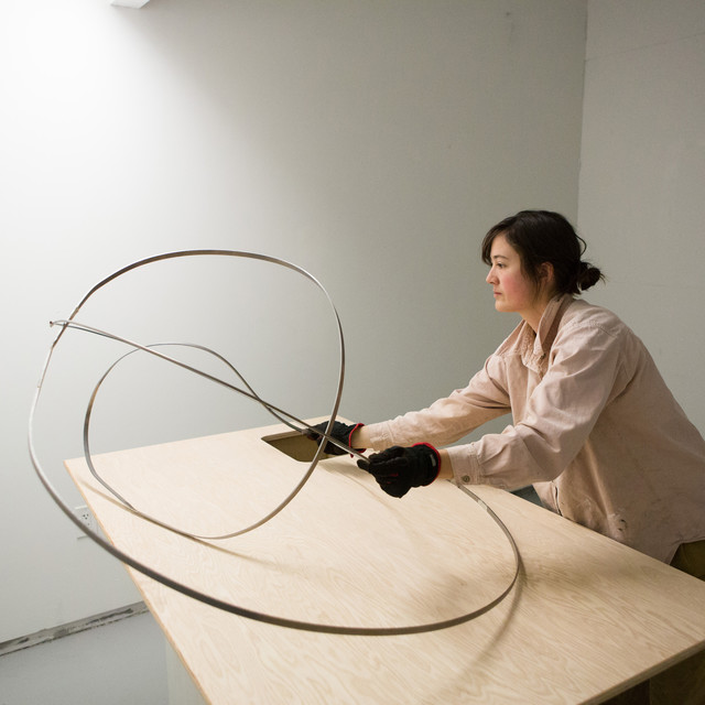 A student shapes metal for her art piece