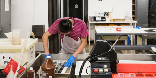 An ArtCenter Photography student develops a black and while photograph in the lab