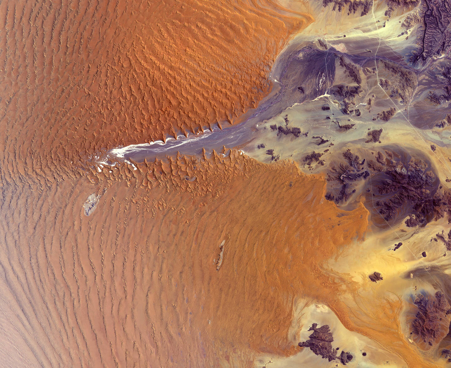 At+fifty-five+million+years+old%2C+the+Namib+Desert%2C+in+western+Namibia%2C+is+considered+the+oldest+desert+on+Earth.+In+this+image+part+of+the+Namib-Naukluft+National+Park+is+visible%2C+which+covers+an+area+of+almost+50%2C000+square+kilometers+%2819%2C300+square+miles%29.+The+park%E2%80%99s+main+attraction+is+Sossusvlei%2C+a+large+white+salt+and+clay+pan+in+the+center+of+the+image.+Sossusvlei+is+a+basin+for+the+Tsauchab+River%2C+an+ephemeral+river+flowing+from+the+east.+The+dunes+in+this+area+are+some+of+the+highest+in+the+world.+The+tallest+stands+at+around+325+meters+%281%2C066+feet%29.+The+Namib+Sand+Sea+is+the+only+coastal+desert+in+the+world+to+contain+large+dune+fields+influenced+by+fog%2C+the+primary+source+of+water.