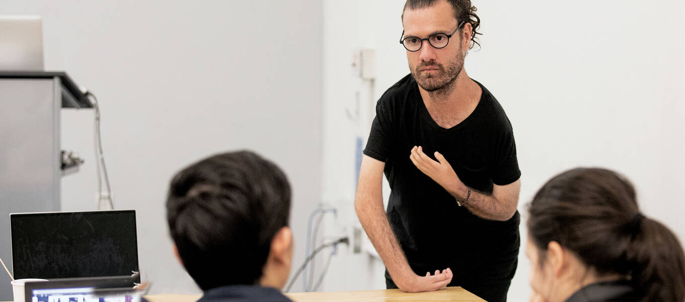 Detail of a photo of Graphic Design alum, disability rights advocate, designer and Designmatters and Interaction Design Assistant Professor Josh Halstead teaching in a classroom, with students in the foreground, about design accessibility.