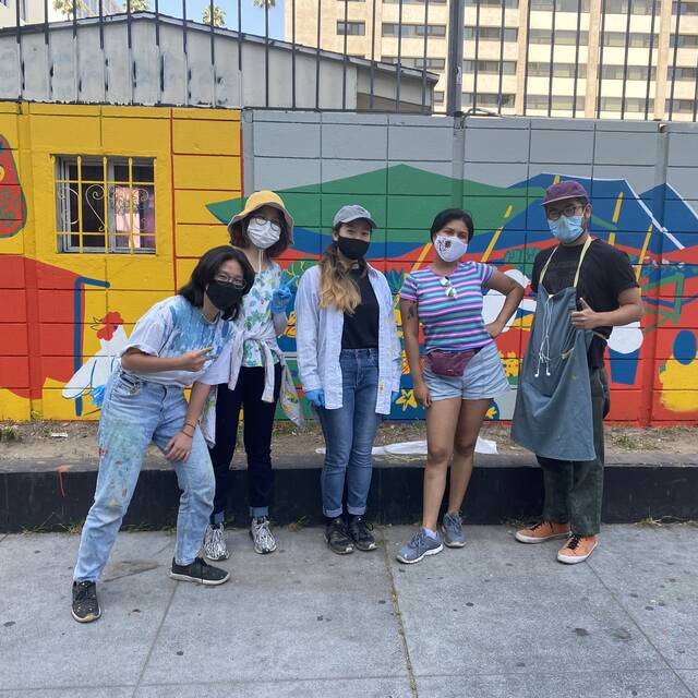 students stand in front of painted mural