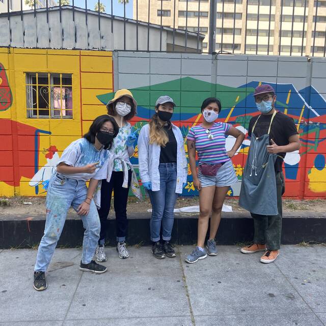 students stand in front of painted mural