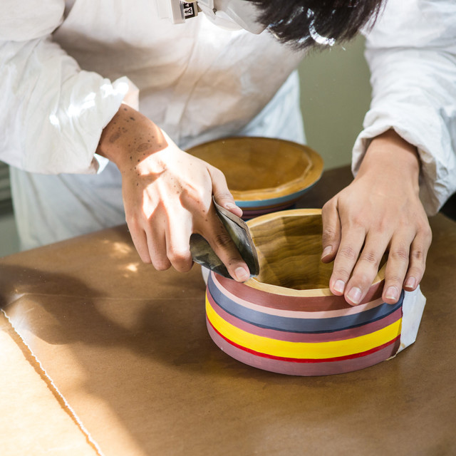 An ArtCenter student sands the edge a handmade wooden bowl