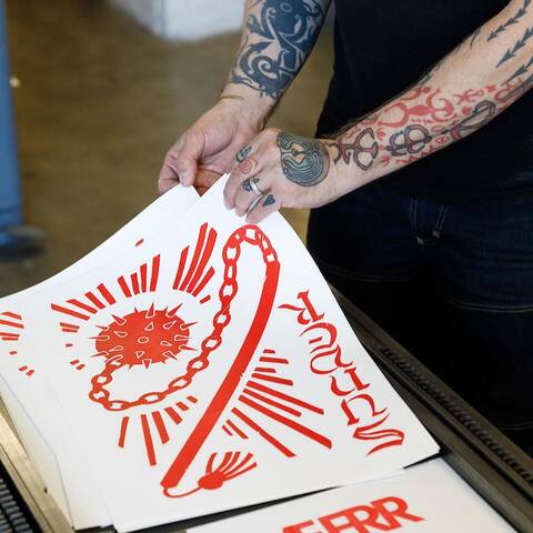 tattooed arms lifting screen printed poster with red design
