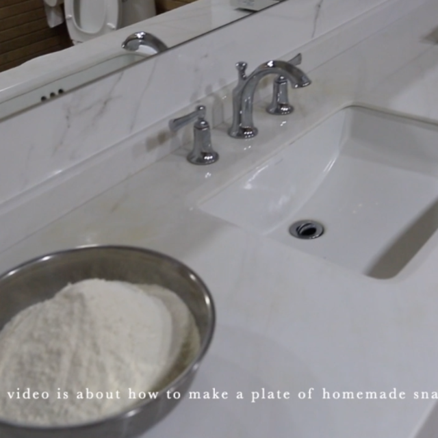 Bowl of flour next too a bathroom sink with marble countertops