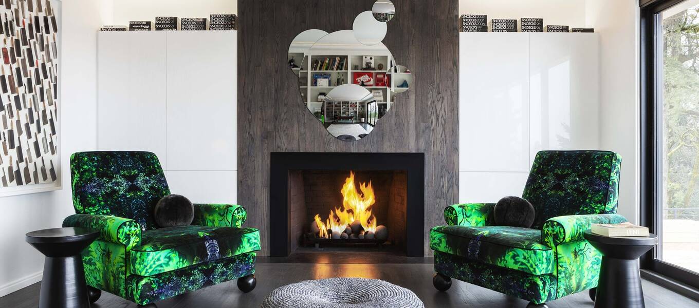 Photo of a man green chairs beside a fireplace