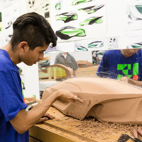 student sculpting car model out of clay