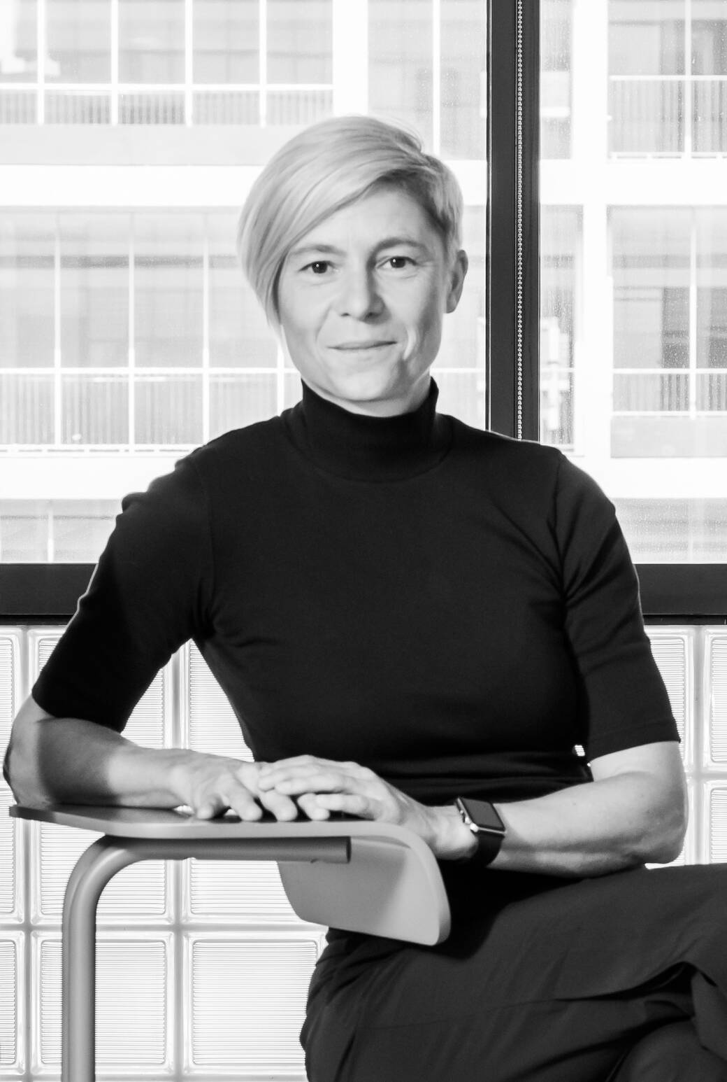 Black-and-white portrait of Sigi Moeslinger, seated at the Toboggan chair desk, which she designed for Knoll.