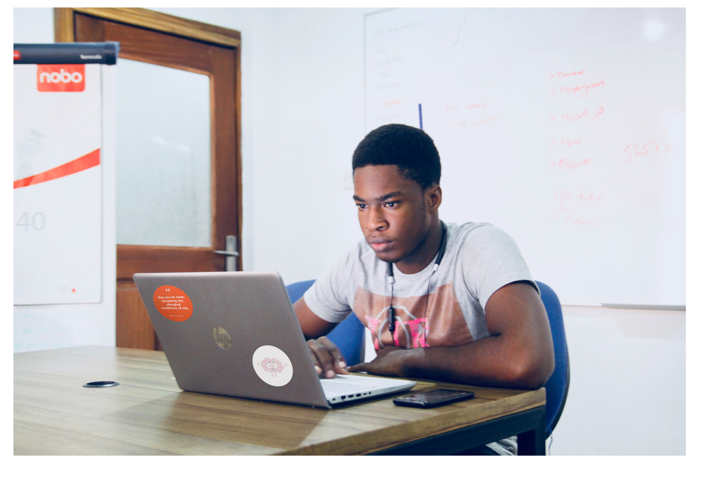 A photo of a teen sitting at a laptop showcasing stickers made for the Me and My Emotions campaign designed by ArtCenter students for a Designmatters class and implemented by a nonprofit partner to help teens with mental wellbeing.