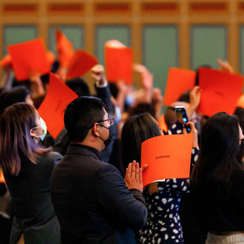 ArtCenter graduates clapping with orange folders