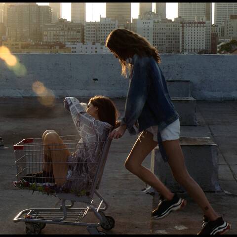 ArtCenter Graduate Film student project featuring a young woman in shorts and a denim jacket pushing another young woman in a shopping cart on a urban rooftop