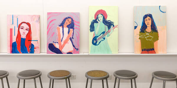 Illustrations lined up along the wall with stools beneath