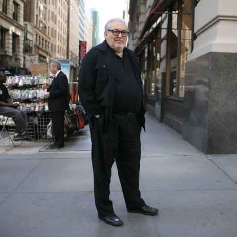 /Man wearing all black standing on a street corner in New York City.