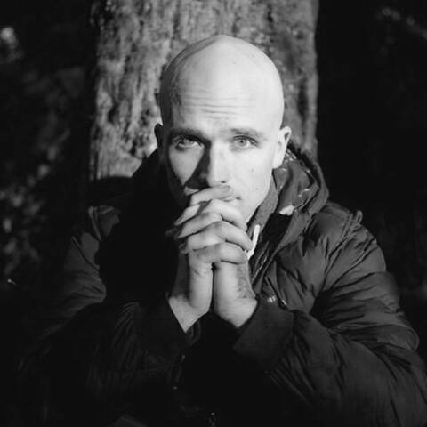 /Charles Hodges sitting next to a tree. Black and white photograph