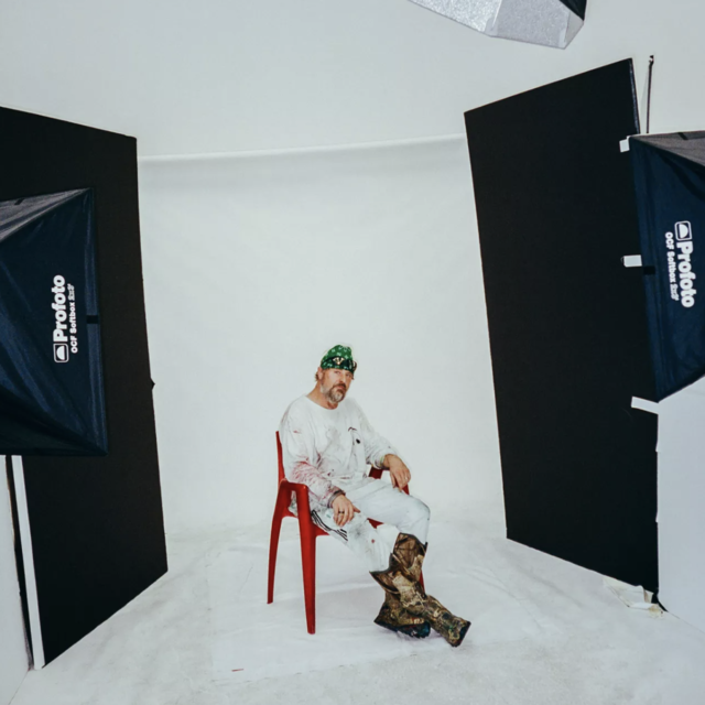 /Sterling Ruby in his LA studio sitting in red chair under a photo light