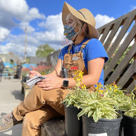 /Estella Tse sits with plants in a garden nursery.