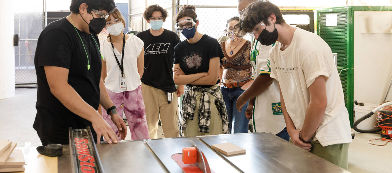 Detail of a photo of First Year Immersion student (middle) Yasmine Gutierrez and Integrated Studies Assistant Professor Robert Lepiz (left) with other students in the course Shop Skills Materials Lab, Fall 2022. Photo by Juan Posada.