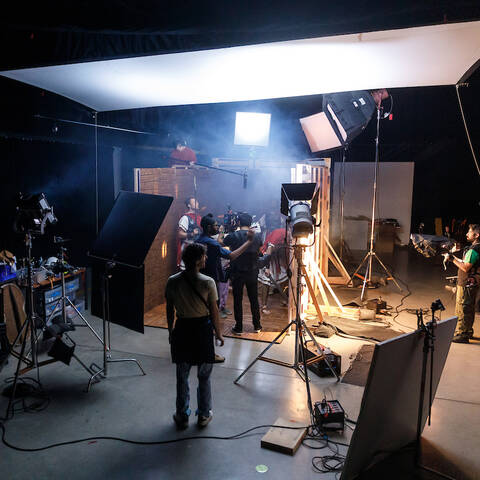 Film students working on a sound stage at ArtCenter, filming a scene with professional lighting, cameras, and set design.