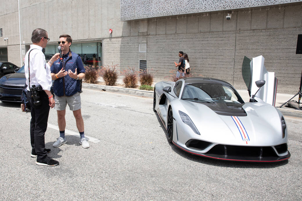 Ed Justice Jr. interviews alum Nathan Malinick (BS 18) next to the silver-colored 2022 Hennessey Venom F5 supercar he designed