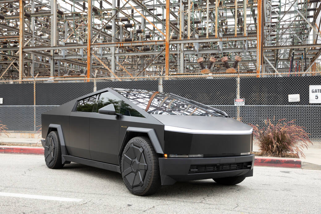 A black-matte painted 2024 Tesla Cybertruck, designed by alum and Trustee Franz von Holzhausen (BS 92) and alum Sahm Jafari (BS 17), parked on a street in front of a power plant