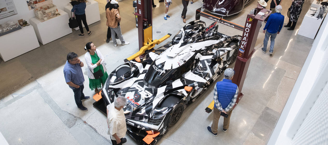 Birds-eye view of visitors studying a 2023 Acura ARX-06, staged indoors.