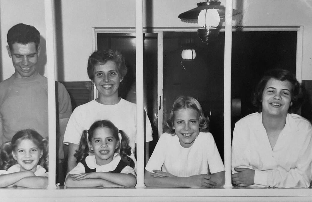 A black-and-white photo from 1967 of Ross and Maberly Player and Madelyn Maberly, taken from outside a house, with each of their daughters framed within a window frame