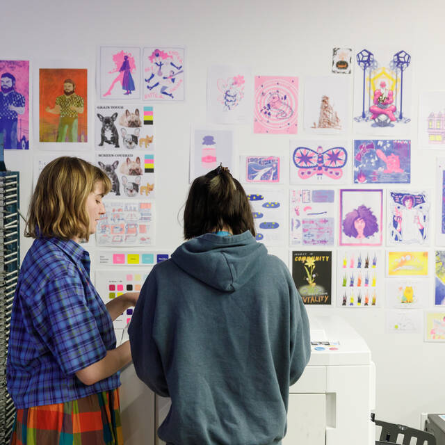 Two ArtCenter students reviewing work in progress in an Illustration workroom.