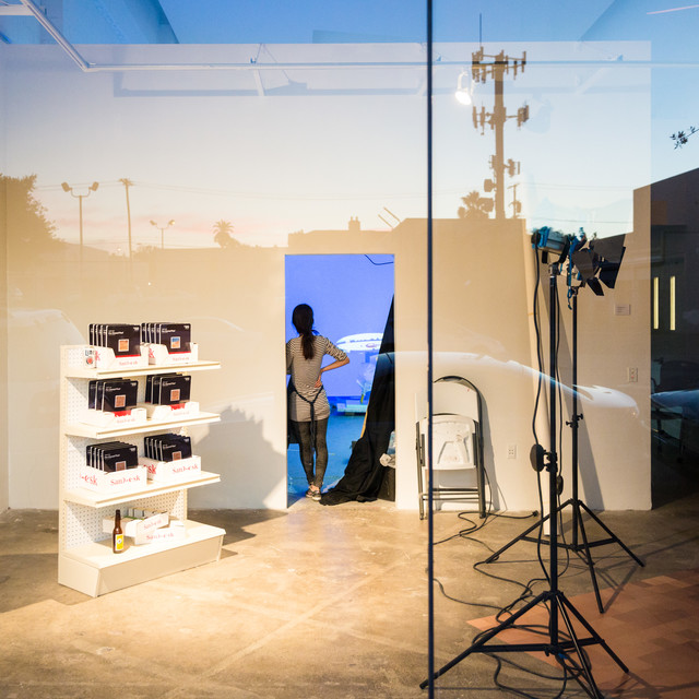 A photoshoot setup as seen through an exterior window with the streetlights and palm trees reflected in the glass