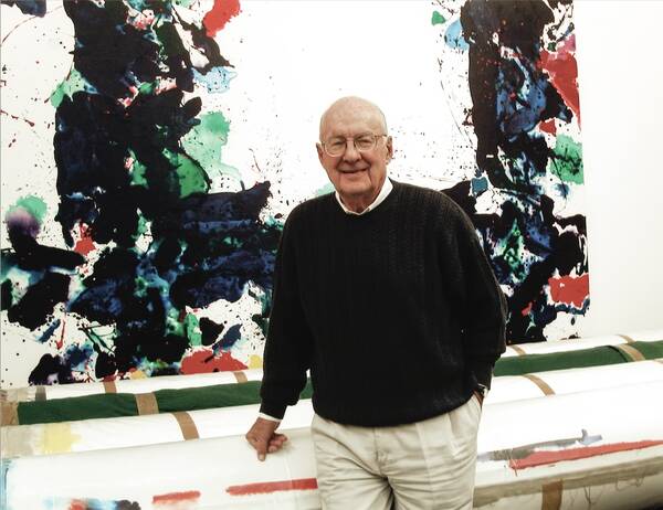 Frederick M. Nicholas standing in front of a Sam Francis painting