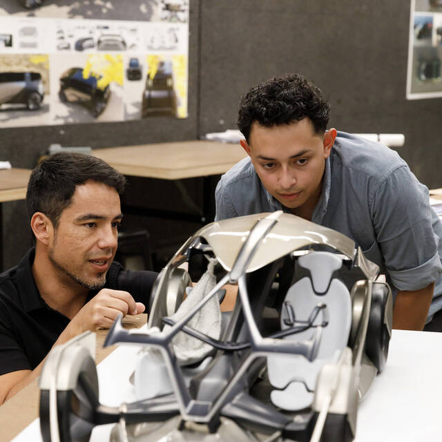 Instructor and graduate student discussing a product mockup during a design critique session.