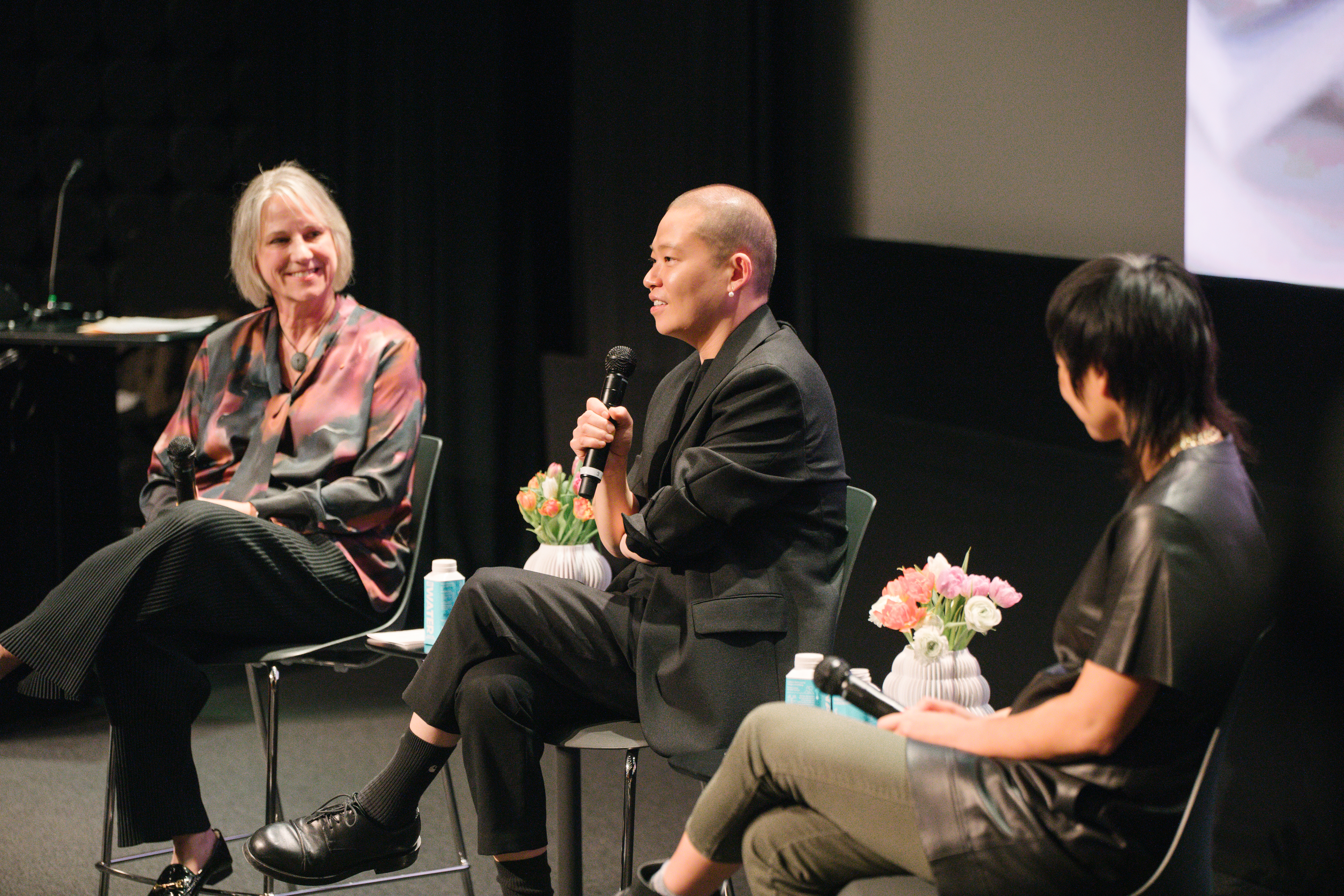 L-R: President Karen Hofmann, fashion designer Jason Wu and faculty member Elise Co seated in a dark auditorium and speaking at ArtCenter