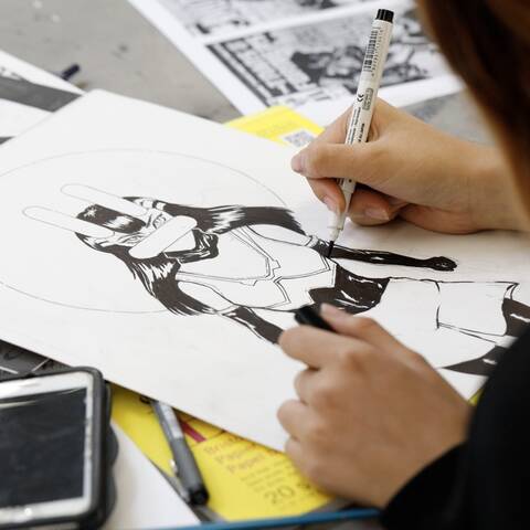 /High school student designing characters and environments in Character and Worlds class at ArtCenter Summer Extension, sketching scenes and figures.