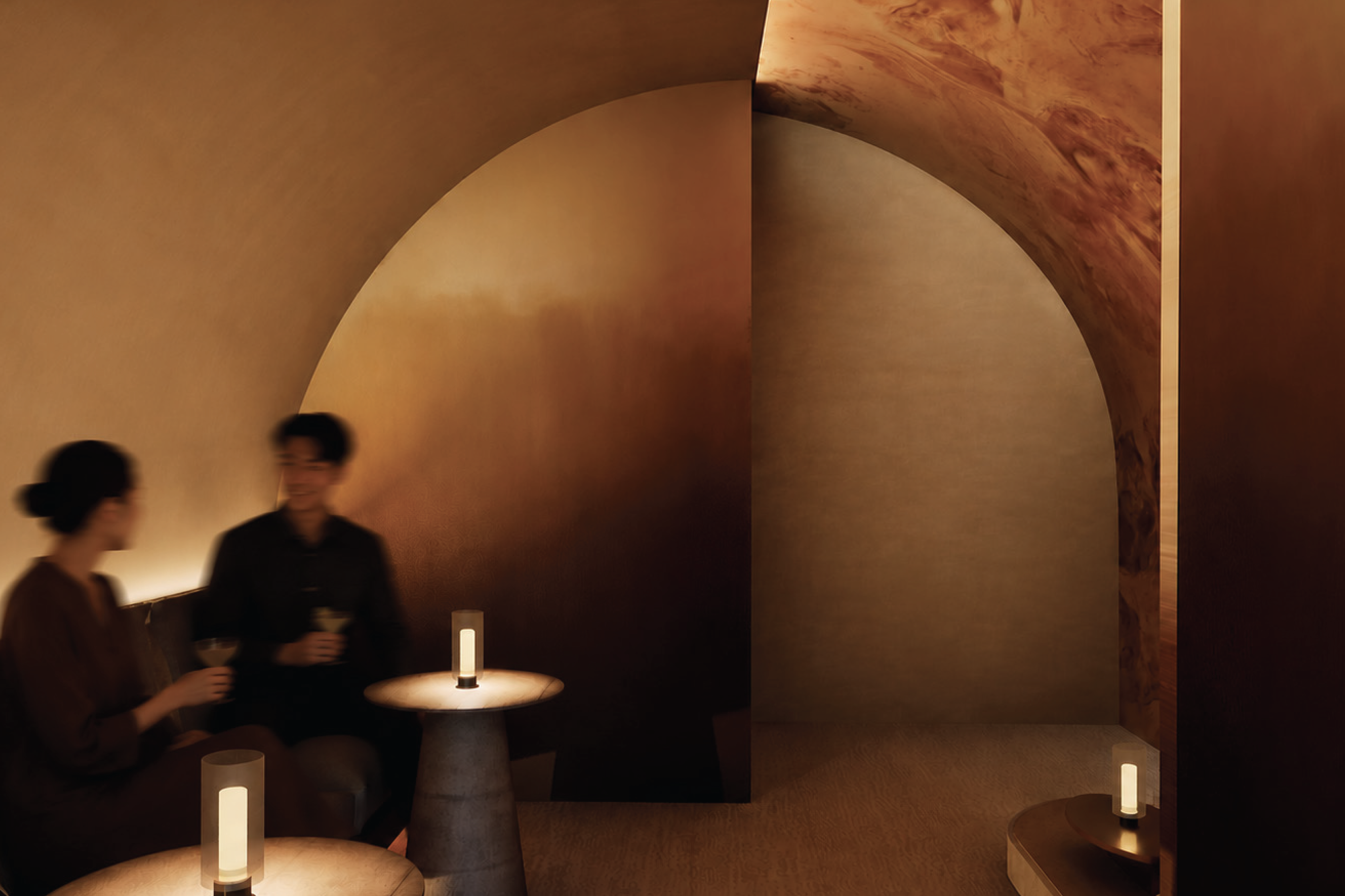 Photo of two seated individuals speaking in a warm, low-lit lounge