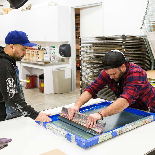 Two students work on an art print in the printmaking studio