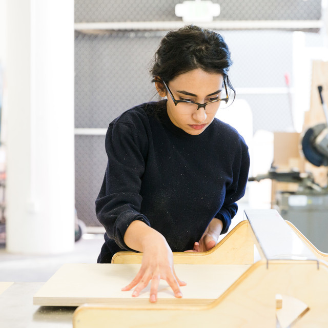 a student aligns wood pieces as she assembles a model