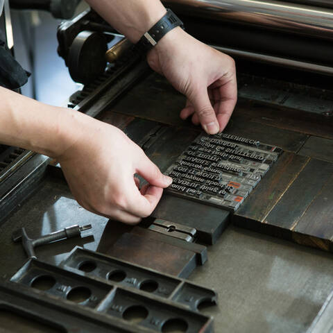 /Detail shot of hands setting metal type in the Archetype Press letterpress studio