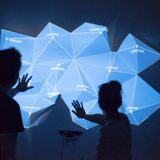 two students silhouetted in front of a projected image on a wall