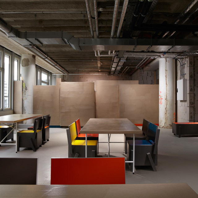 industrial office space with long tables and colorful chairs