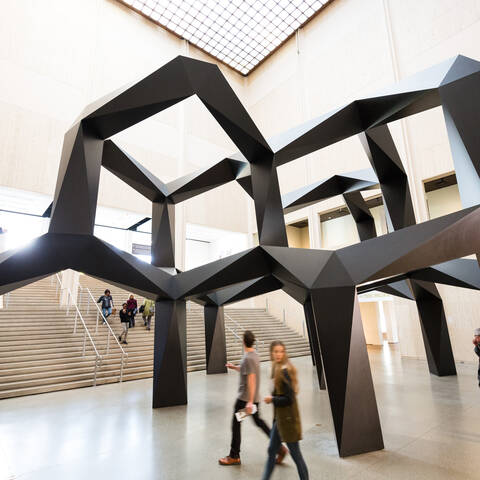 people walking under giant sculpture